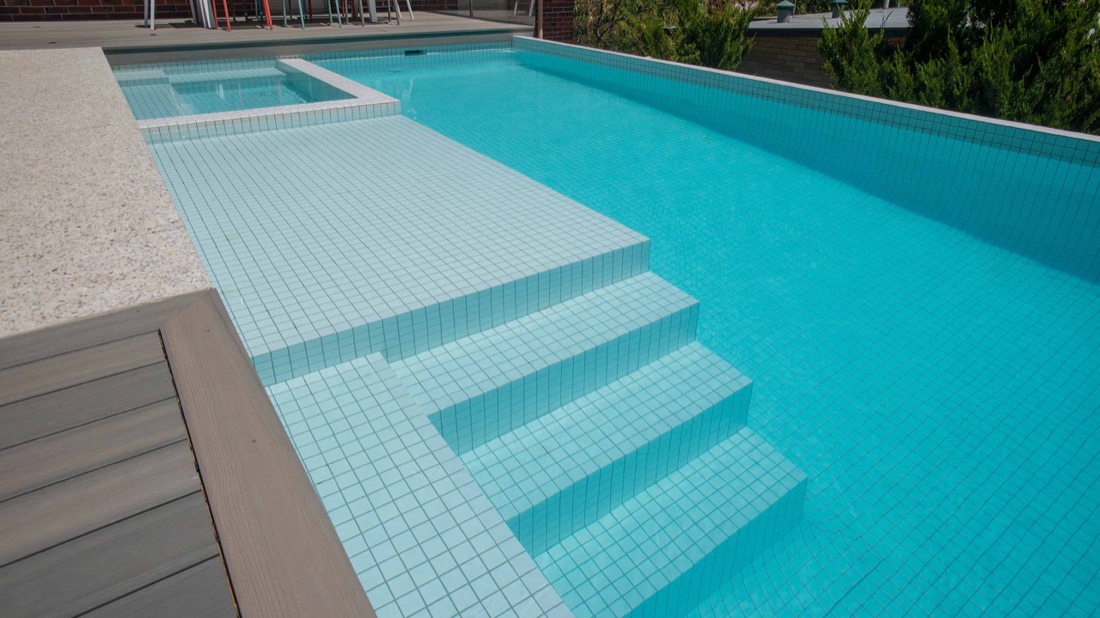 Pale tiled steps and an integrated spa in a Peressin Pools swimming pool